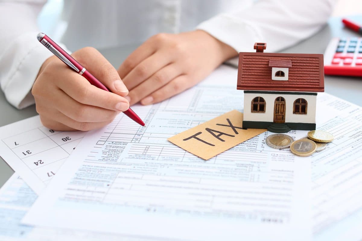 Woman Completes Tax Form with House and Coins